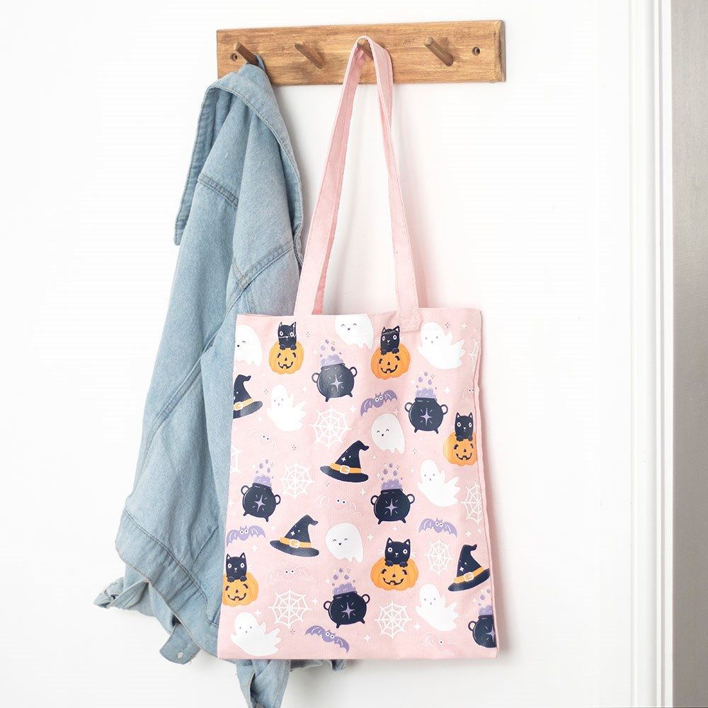  Cute Halloween Print Tote Bag featuring cute ghosts, bats, pumpkins and cats print against a pink background. This polycotton canvas tote bag is perfect for carrying all your essentials and adding some fun, spooky, pastel gothic vibes to your wardrobe