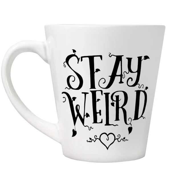 A white latte style mug with fancy black writing saying Stay Weird and a love heart