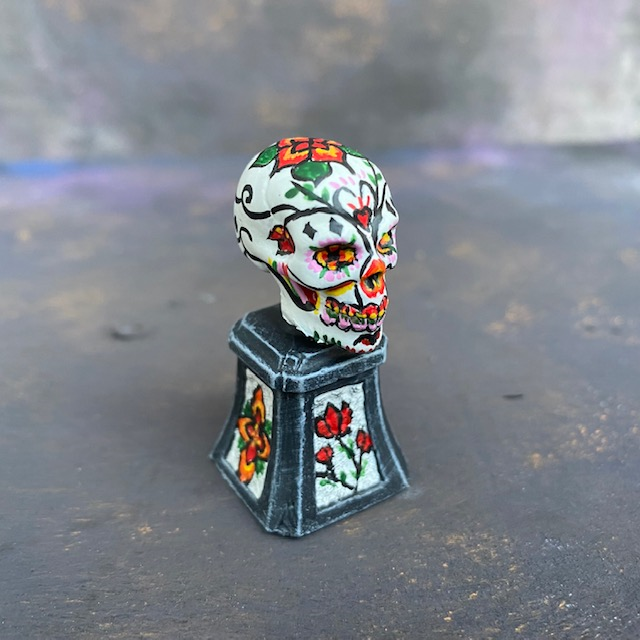 Prepainted Sugar Skull from the Reaper Miniatures bones USA range hand painted by Mrs MLG, a brightly coloured skull on a plinth.