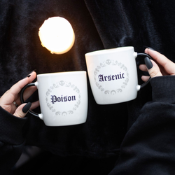 A set of two white mugs with a black handle and inside featuring a grey circle pattern with crescent moon, swirls and skull design with one mug having the word Poison and the other saying Arsenic in black writing. Sold as a set of two mugs with a 350ml capacity to add a little dark humour to your morning coffee. &nbsp;