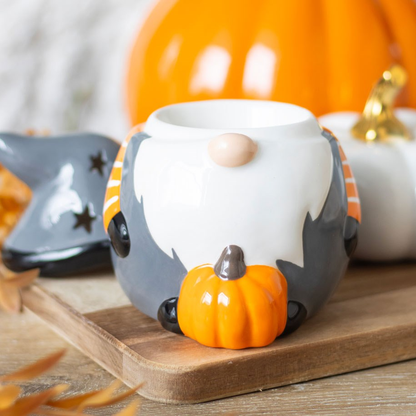 Add a touch of Halloween charm to your home with this Halloween Gonk Oil Burner. This festive gonk, wearing a grey top with orange and white stripe sleeves, features a star cut out design on the hat giving a magical glow, making it the perfect seasonal décor. Bring the magic of Halloween into your space with this cute oil burner