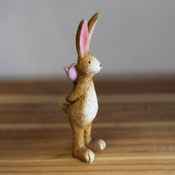 Standing Rabbit With Rose. A cute bunny figurine standing and holding a pink rose behind its back making an adorable gift or edition to your homeware decoration.