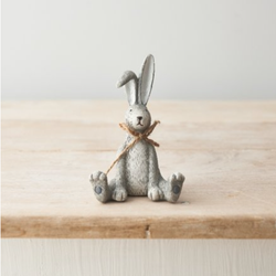 Sitting Grey Rabbit With A Bow. An adorable bunny figurine sitting down  with its legs out in front and its front paws in between, having one ear bent and wearing a jute bow. A quirky animal decoration for yourself or as a gift.  