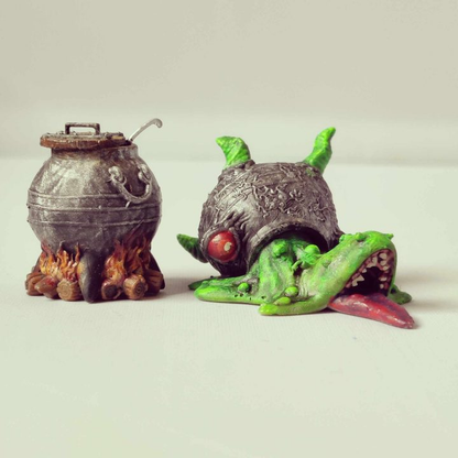 Cauldron Cart by Iron Gate Scenery.&nbsp; A 28mm scale printed resin miniature.&nbsp; A pack of two miniatures one representing a pot over a lit fire and the other its true form a slimy, tooth filled mimic&nbsp;making a perfect edition to your RPG table