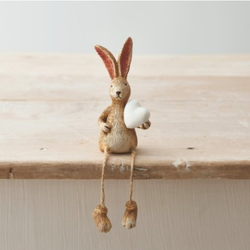Shelf Sitting Rabbit With White Heart with dangly legs. A cute bunny figurine holding a white heart that can sit on a shelf with its legs dangling over the edge, a wonderful edition to your home decor or as a gift. 
