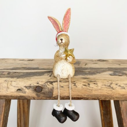 Sitting Santa Rabbit With Star.  A beautiful sitting bunny ornament with dangly legs wearing black boots, a Santa hat  and holding a gold star