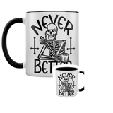 Never Better Skeleton Mug. A white mug with a skeleton holding a mug and thumbs up with the words Never Better in black, a black inner and handle