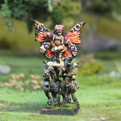 Fae Queen by Oakbound Studio. A multipart lead pewter miniature supplied with a 60mm round lipped bases. The Queen wears a skeleton mask and rides upon her throne carried by donkey like creatures with her glorious wings outstretched