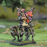 Fae Queen by Oakbound Studio. A multipart lead pewter miniature supplied with a 60mm round lipped bases. The Queen wears a skeleton mask and rides upon her throne carried by donkey like creatures with her glorious wings outstretched