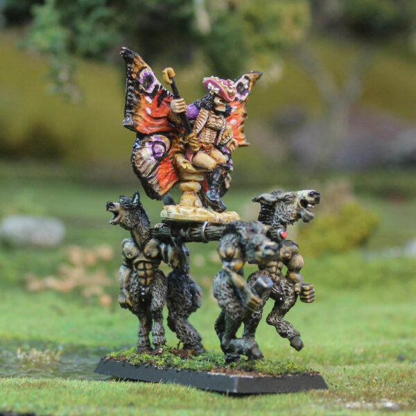 Fae Queen by Oakbound Studio. A multipart lead pewter miniature supplied with a 60mm round lipped bases. The Queen wears a skeleton mask and rides upon her throne carried by donkey like creatures with her glorious wings outstretched