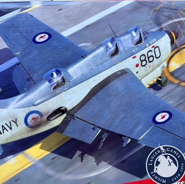 A printed or illustrated aircraft scene showing a silver military plane on an airport runway, with visible roundel insignias and the number 860. A circular 'Mighty Lancer Games' logo appears in the lower right corner. Airfix Fairey Gannet AS.1/AS.4 Export Schemes  1:48 Aircraft Kit