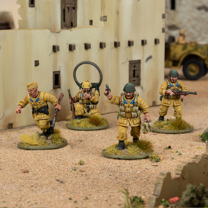 Toy soldiers in desert setting with a building and vehicle in the background
