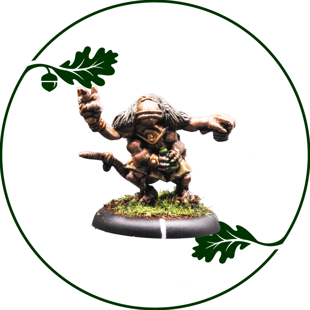 A painted fantasy miniature of a goblinoid creature crouching on a round mossy base, centered inside a circular frame with green oak leaves and an acorn graphic on a white background. Fenfolk Uruor by Oakbound Studio