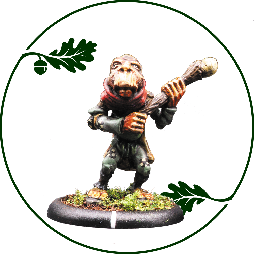 A painted fantasy miniature figurine of a small ape-like creature holding a staff, standing on a mossy base with an oak leaf and acorn motif in the background on a white field. Hillfolk Chornicrow by Oakbound Studio