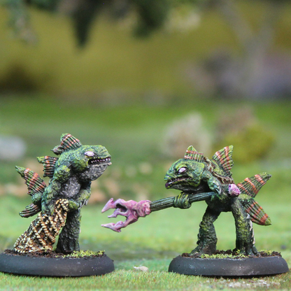 Oakbound Studio Bucca Raiders. Two miniature figures of green creatures with pink appendages on a grassy background