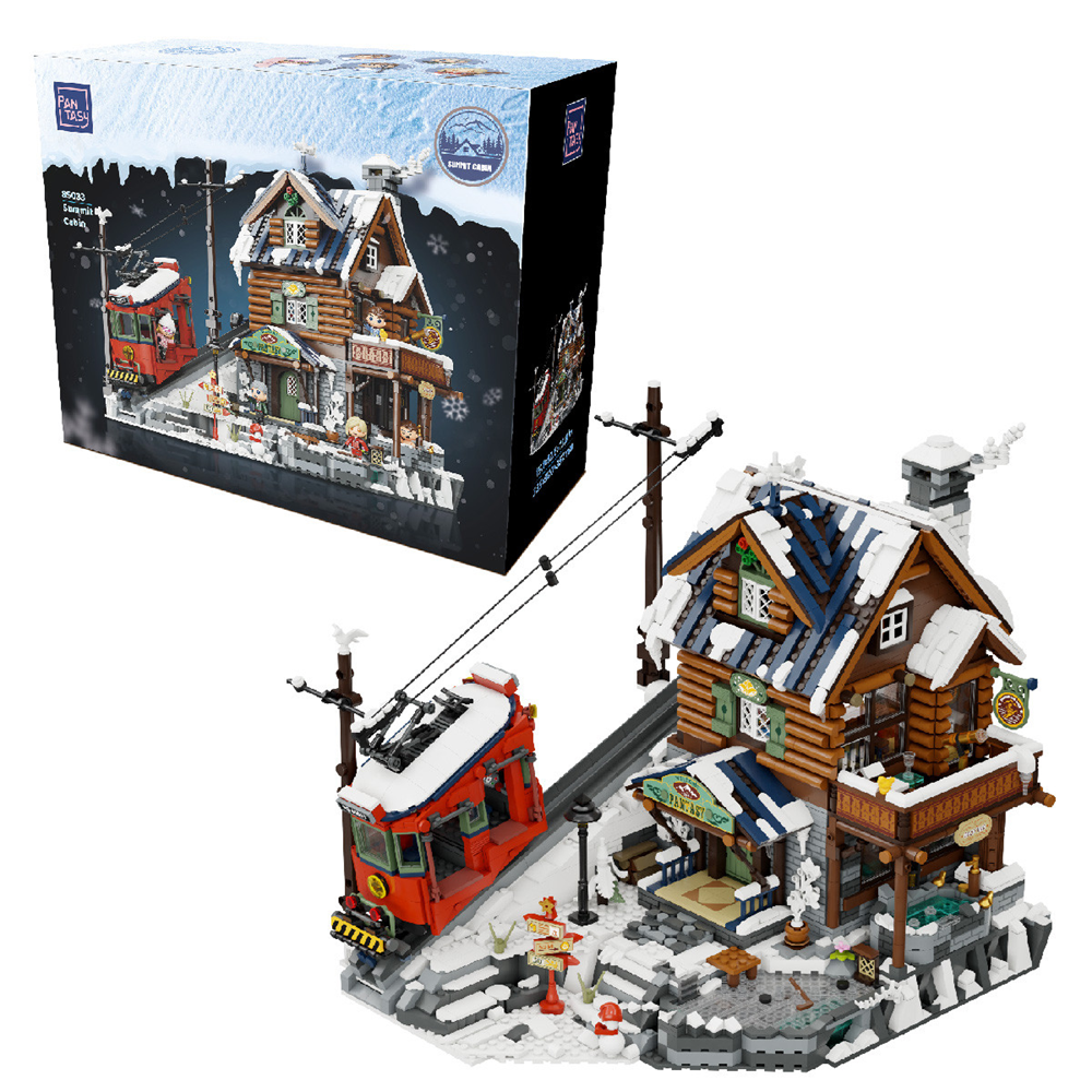 Model of a snowy village scene with a building and trolley, next to its packaging. PanTasy Mountain Summit Ski Cabin brick model kit with cable car and 3135 pieces