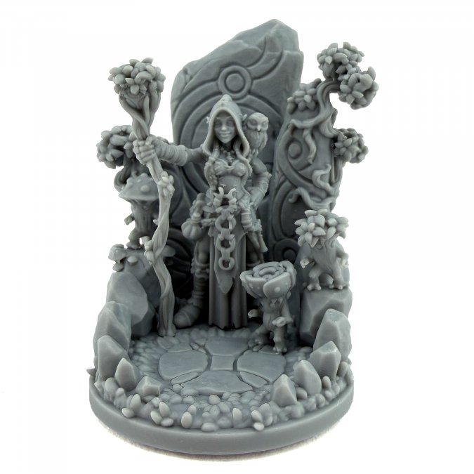 A gray unpainted resin miniature figurine of a fantasy female ranger character standing in a detailed rocky forest scene with trees, rocks, and a circular base, photographed on a white background. Fern Emervale Wildbloom Witch