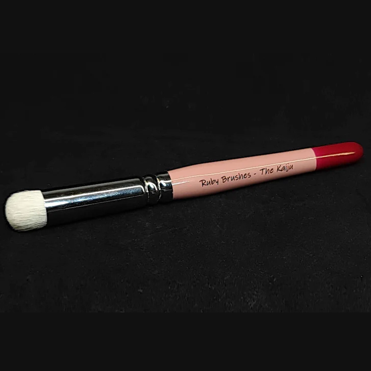 Ruby Brushes The Kaiju Drybrush. miniature painting brush with pink handle and black ferrule on a black background