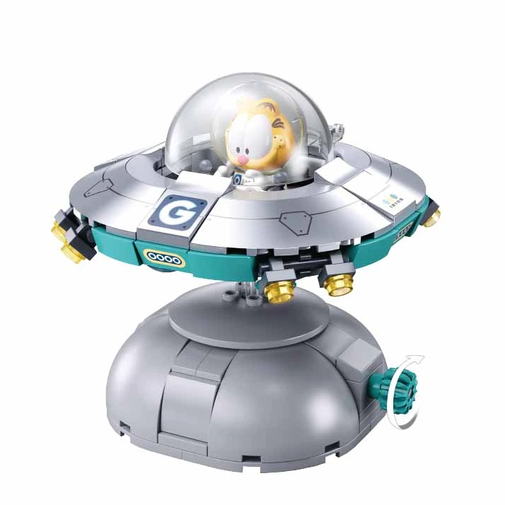 A toy building block model of a flying saucer hovering above a dome-shaped base, featuring a small Garfield figure inside a clear cockpit, on a plain white background. Sluban Garfield Space Ship 193 piece brick building kit with Garfield astronaut