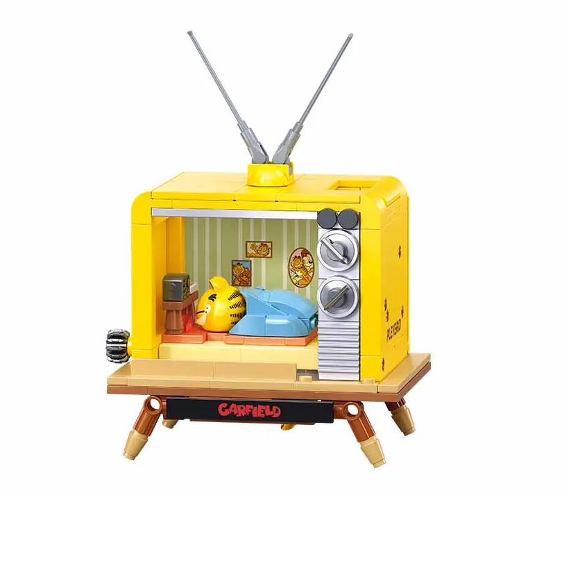 A toy building block set of a retro television set, featuring a bright yellow body, silver dials, wooden legs, and a small interior scene with a yellow bear and blue blanket, shown on a plain white background. Sluban Garfield TV 193 piece brick building kit with sleeping Garfield diorama