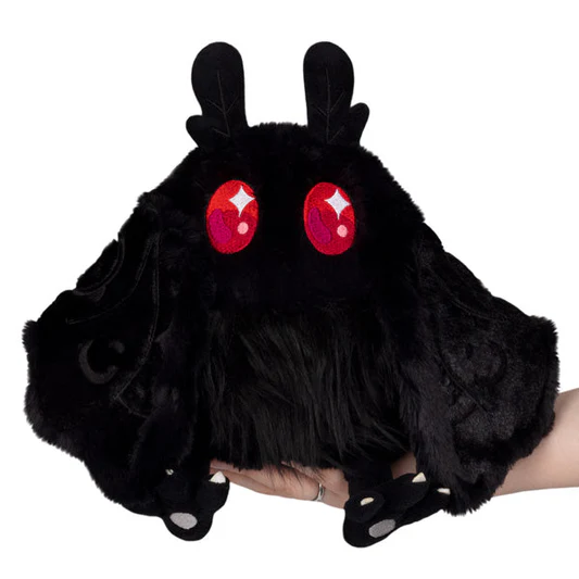 Black plush toy with red eyes held by a hand on a white background. Squishable Baby Mothman