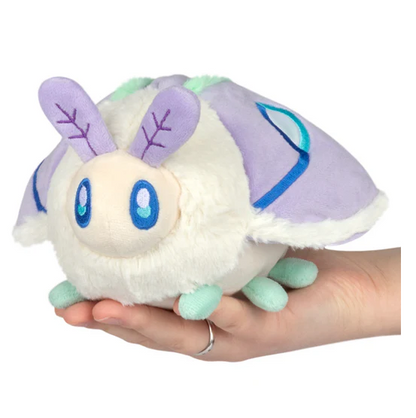 Plush toy resembling a creature with a white body, purple and blue accents held in a hand against a white background. Squishable Party Snacker Lilac Luna Moth