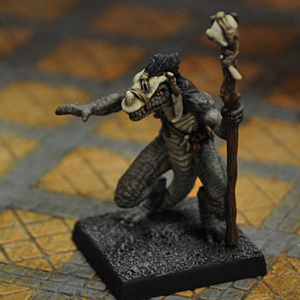 Troglodytes Shaman by Crooked Dice. A metal miniature representing a lizard man with primitive staff and skull mask making a great edition to your RPGs and tabletop gaming