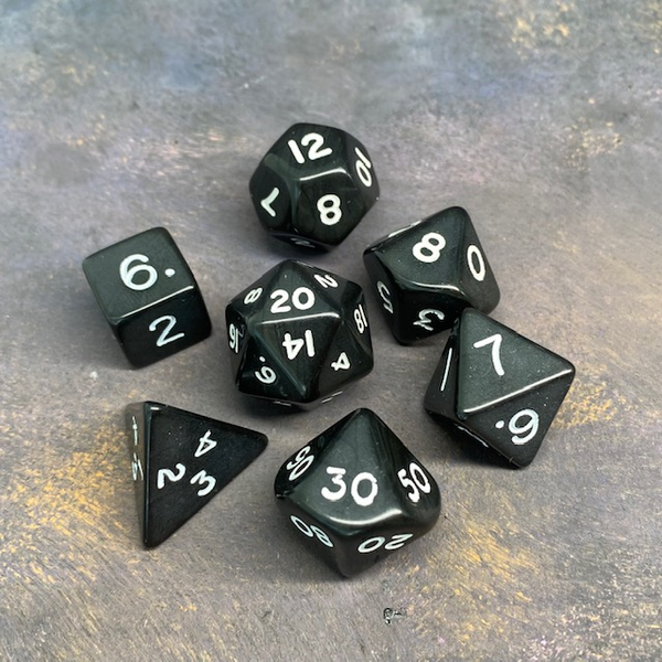 7 black RPG dice with white numbers.