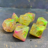 7 RPG dice with gold numbers and pink and green swirled colours.