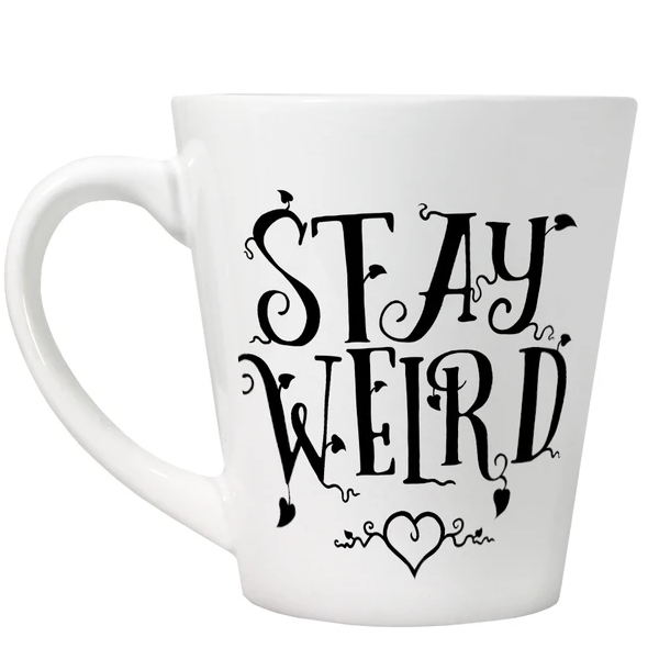 A white latte style mug with fancy black writing saying Stay Weird and a love heart 