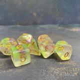 A set of 7 glitter dice having gold numbers and suffused with glitter and green and pink colours. 