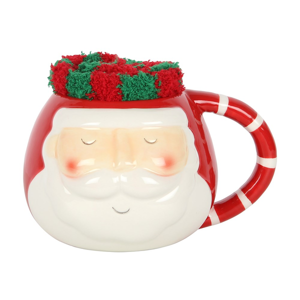  A rounded mug with Santa face design and red and white stripe handle with a pair of red and green stripped fluffy socks