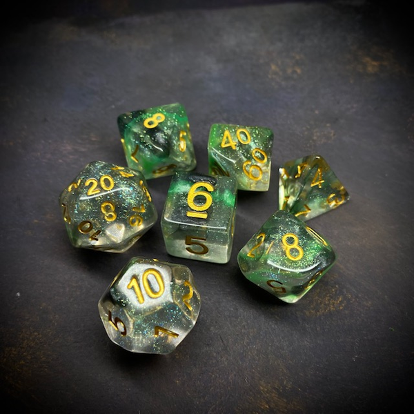 A set of glitter translucent dice suffused with green colours and gold glitter. The numbers on these dice are also gold.