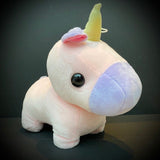 A super cute cuddle club pink chibi unicorn with a peach star detail, yellow horn, purple mane, tail and muzzle, large head and stumpy legs in the typical chibi style.