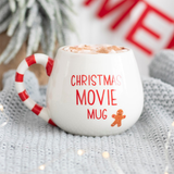 white rounded mug features a red and white stripe handle, the words 'Christmas Movie Mug' in red and a smiley gingerbread character.