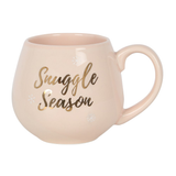 A beautiful soft pink coloured rounded mug with gold writing saying 'Snuggle Season'.