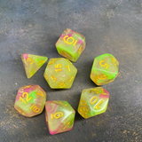 7 RPG dice with gold numbers and pink and green swirled colours.