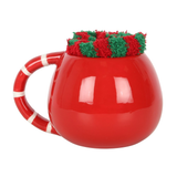  A rounded red mug  and red and white stripe handle with a pair of red and green stripped fluffy socks in the top 