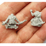 Ugruk-tar Goblin Mercenaries by Spellcrow. A pack of 2 resin miniatures and 2 bases (25mmx25mm) depicting Goblins, one wearing a mask, fur shawl and a dagger behind his back and the other holding the dagger out to the side and his bottom exposed. These are shown being held in a hand