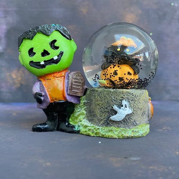 Spooky snowglobe halloween decoration. This ornament features Frankenstein's Monster next to a globe which has black 'snow' and a black cat inside a pumpkin. 