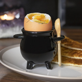 black cauldron egg cup and broom spoon with open egg