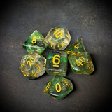 A set of glitter translucent dice suffused with green colours and gold glitter. The numbers on these dice are also gold.