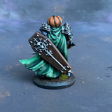 A Reaper Miniature Halloween Knight hand painted by Mrs MLG, a fierce pumpkin headed warrior wearing armour, holding a sword in one hand and a coffin lid shield in the other with a green cape flapping behind. 