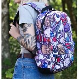 A super cute and funky backpack covered in colourful characters from vampire lips to sharks, lightening cloud to bunny and lots more in between. shown here being worn by a lady with blue jeans, grey t short, tattoos and blonde hair