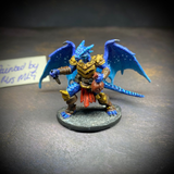  dragonfolk rouge holding a dagger in one hand and a pouch in the other. Mrs MLG has painted this miniature with a blue palette adding white dot effects to the wings, the armour is golden colour and Tazythas has a red loin cloth.