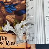The Dragon Rider by Northumbrian Tin Solider is a metal miniature of a teddy bear wearing a cloak, carrying a wooden sword and playing with a dragon hobby horse. 