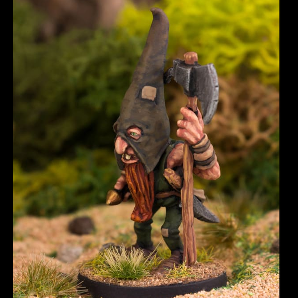 The Woodsman by Northumbrian Tin Solider has a large pointed hat with eye holes, a beard hanging down and a long handled axe in one hand.