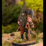 The Woodsman by Northumbrian Tin Solider has a large pointed hat with eye holes, a beard hanging down and a long handled axe in one hand.