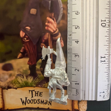 The Woodsman by Northumbrian Tin Solider has a large pointed hat with eye holes, a beard hanging down and a long handled axe in one hand. Shown with a ruler